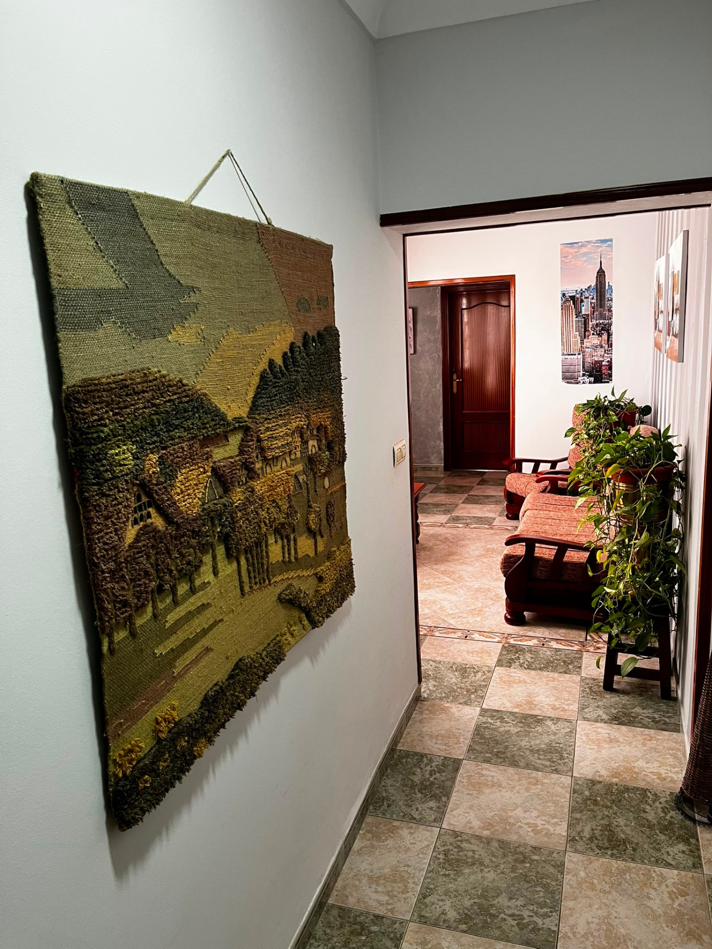 Pasillo con tapiz artesanal y vistas al salón común
